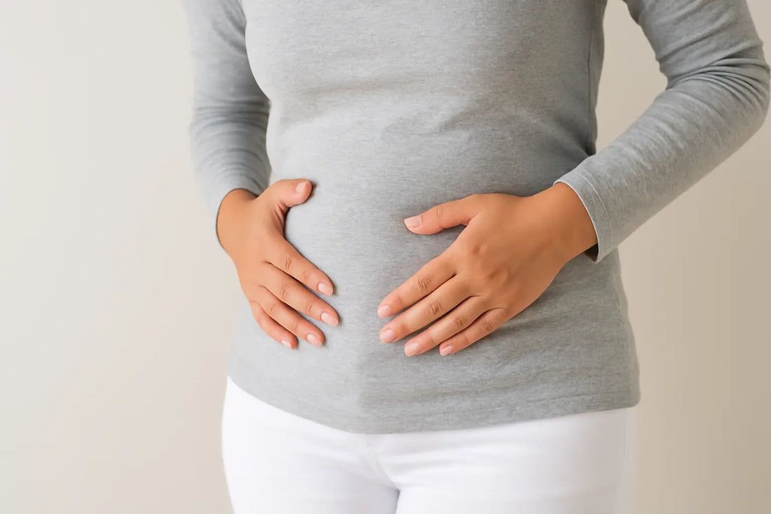 Blähbauch Ursachen: Frau mit Händen auf bauch, die Symptome von Blähbauch zeigt.