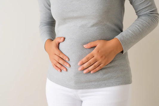 Blähbauch Ursachen: Frau mit Händen auf bauch, die Symptome von Blähbauch zeigt.